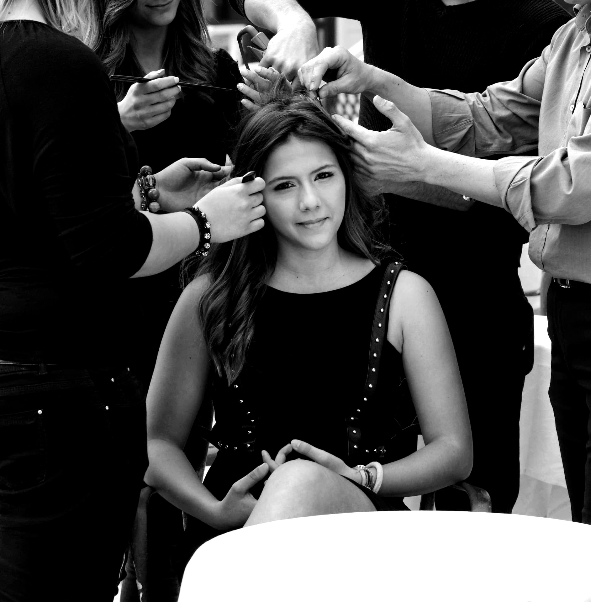 Four pairs of hands working on one model's hair at once